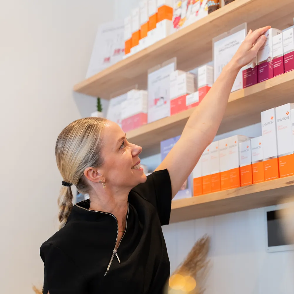 Gemma selecting Environ skincare from the salon product shelves